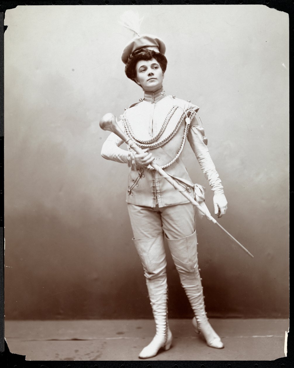 A woman modeling a band uniform, holding a baton by Byron Company