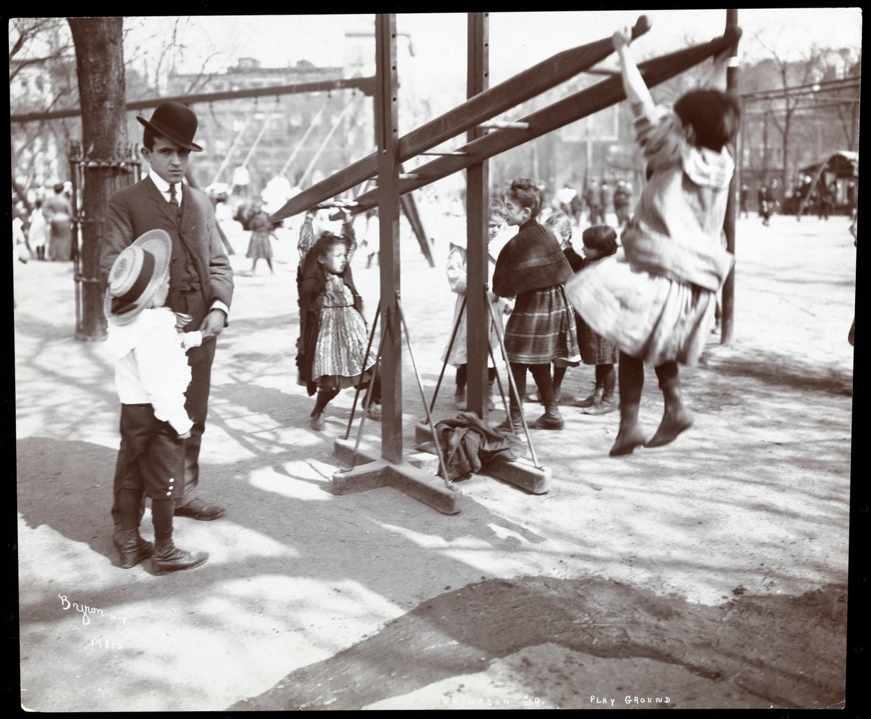 View of a man overseeing children playing on playground equipment at Tompkins Square Park, on Arbor Day, New York by Byron Company