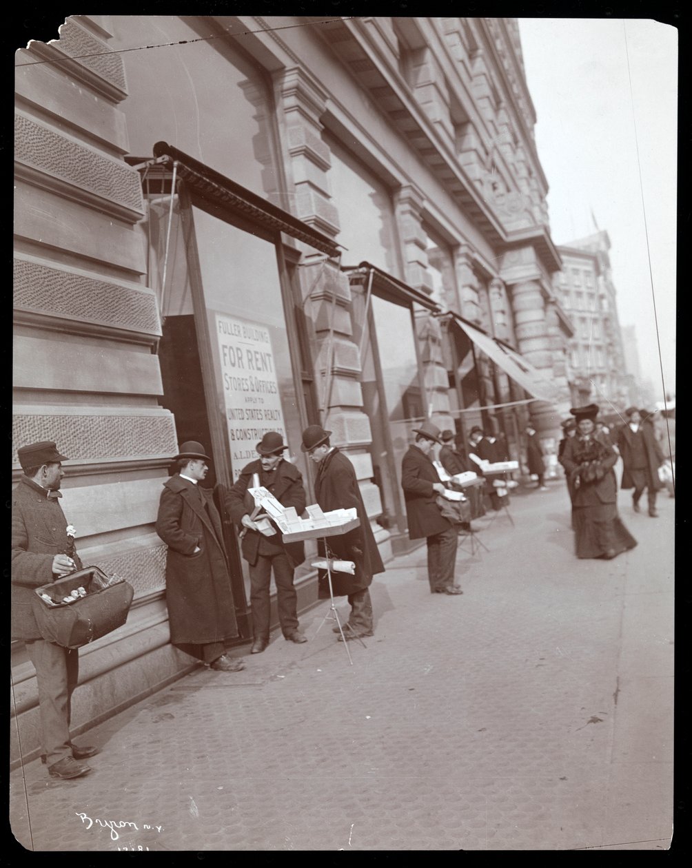 View of peddlers selling toys and other items in front of the Fuller or Flatiron Building at Broadway, 5th Avenue and 23rd Street, New York by Byron Company