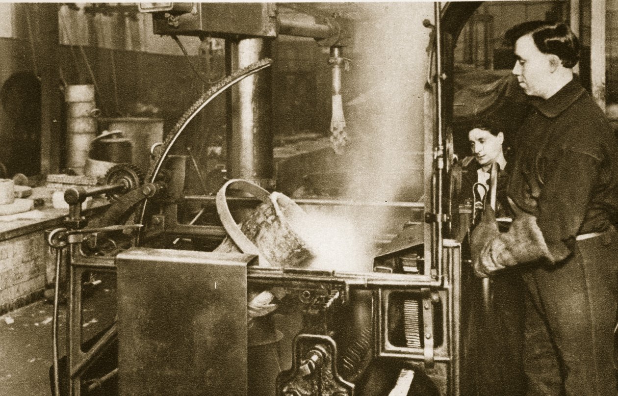 Making money-lowering a pot of liquid metal into a machine by English Photographer