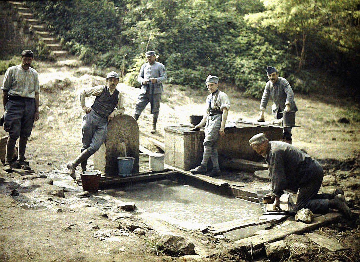 Six French soldiers with buckets and laundry at a fountain, Soissons, Aisne, France, 1917 by Fernand Cuville