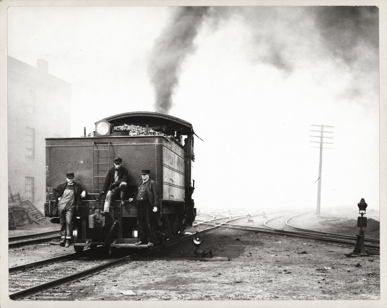 Three Men on the Back of a Switch Engine in an Unidentified Rail Yard by Unknown